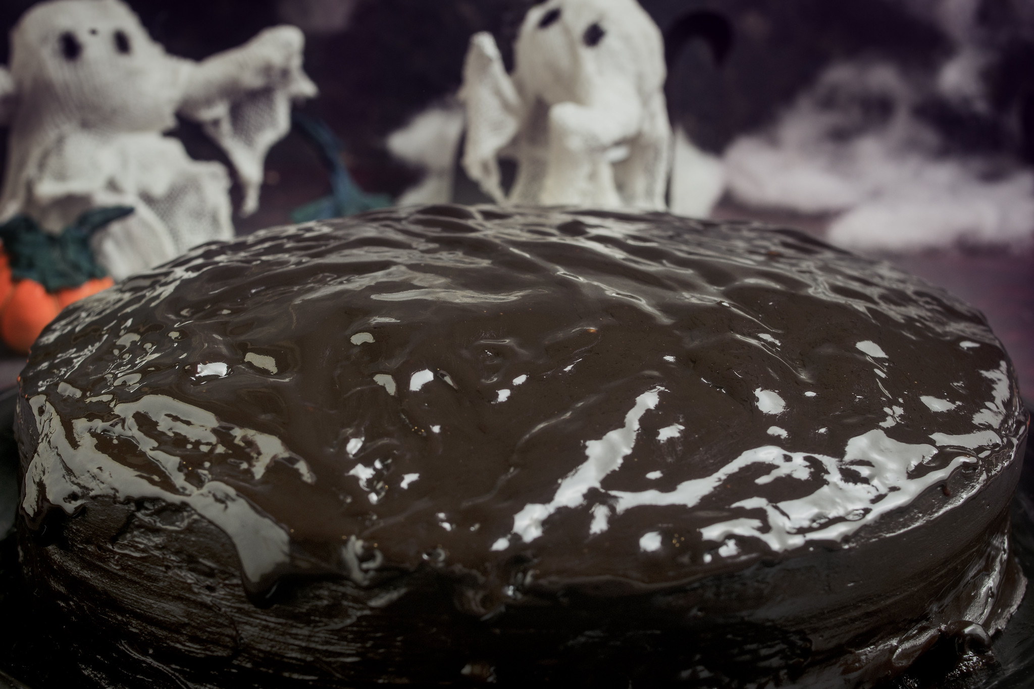 Chocolate Ghoulyard Cake with glossy dark chocolate ganache and ghost decorations for Halloween.
